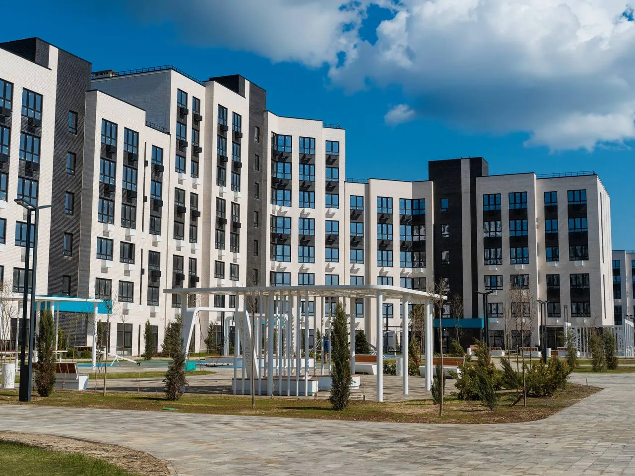 Современный жилой комплекс с многоквартирными домами и благоустроенным двором рядом с морем
